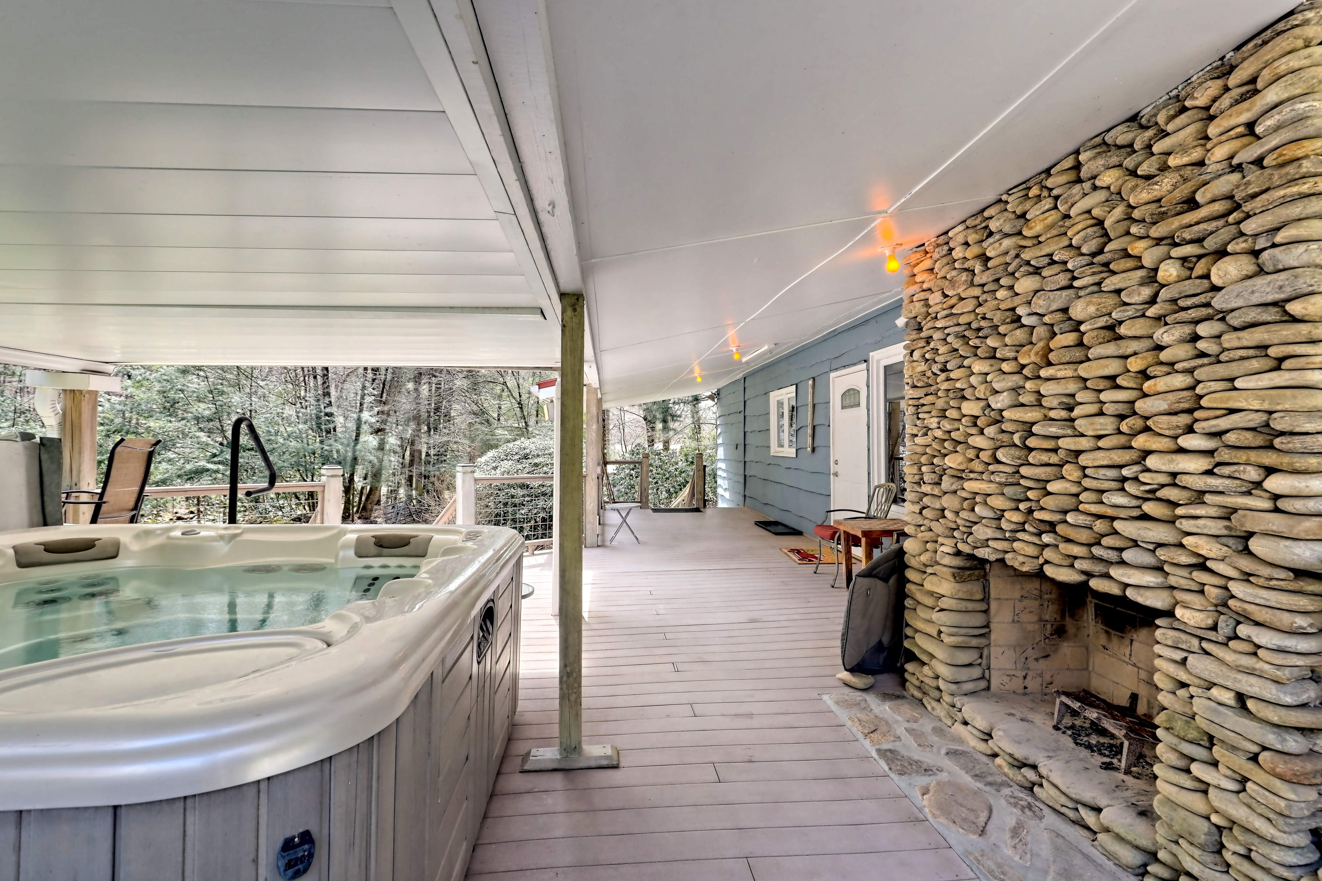 Covered porch with hot tub and large stone fireplace